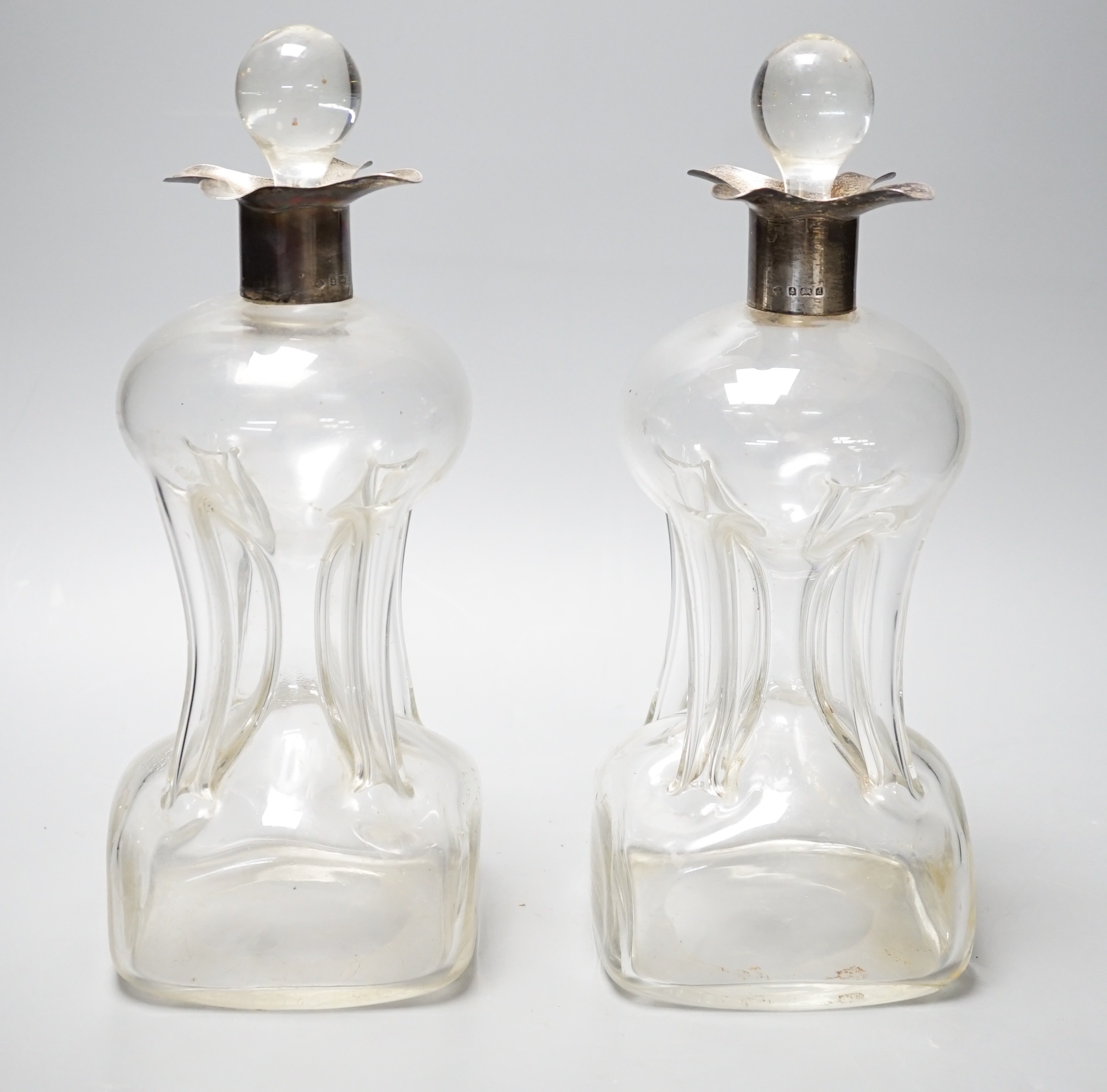 A pair of Edwardian silver mounted hourglass shaped glass decanters with stoppers, by William Hutton & Sons, Birmingham, 1903, overall height 27.5cm.